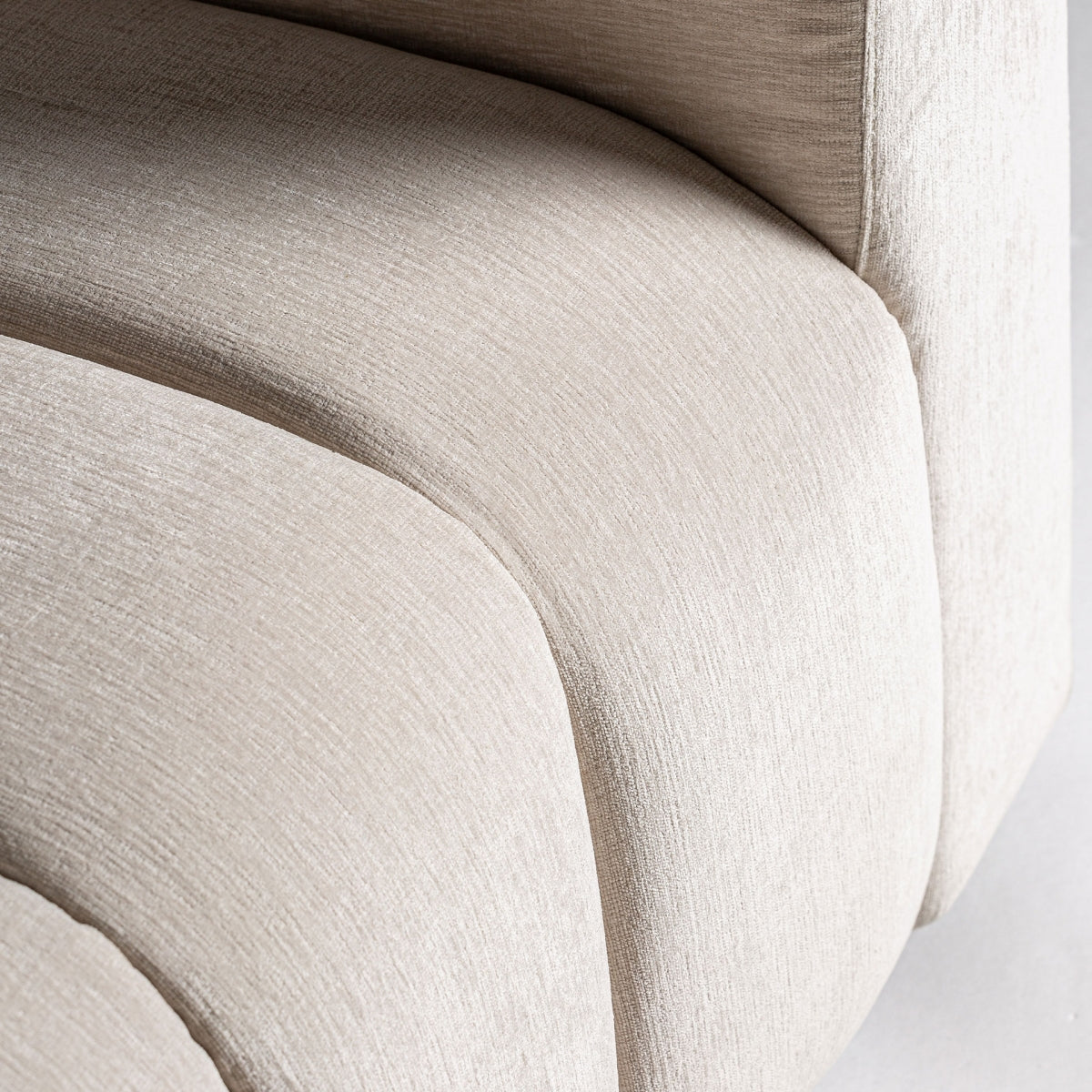 Vista cercana del tapizado acolchado beige del sillón, costuras verticales elegantes, textura suave
