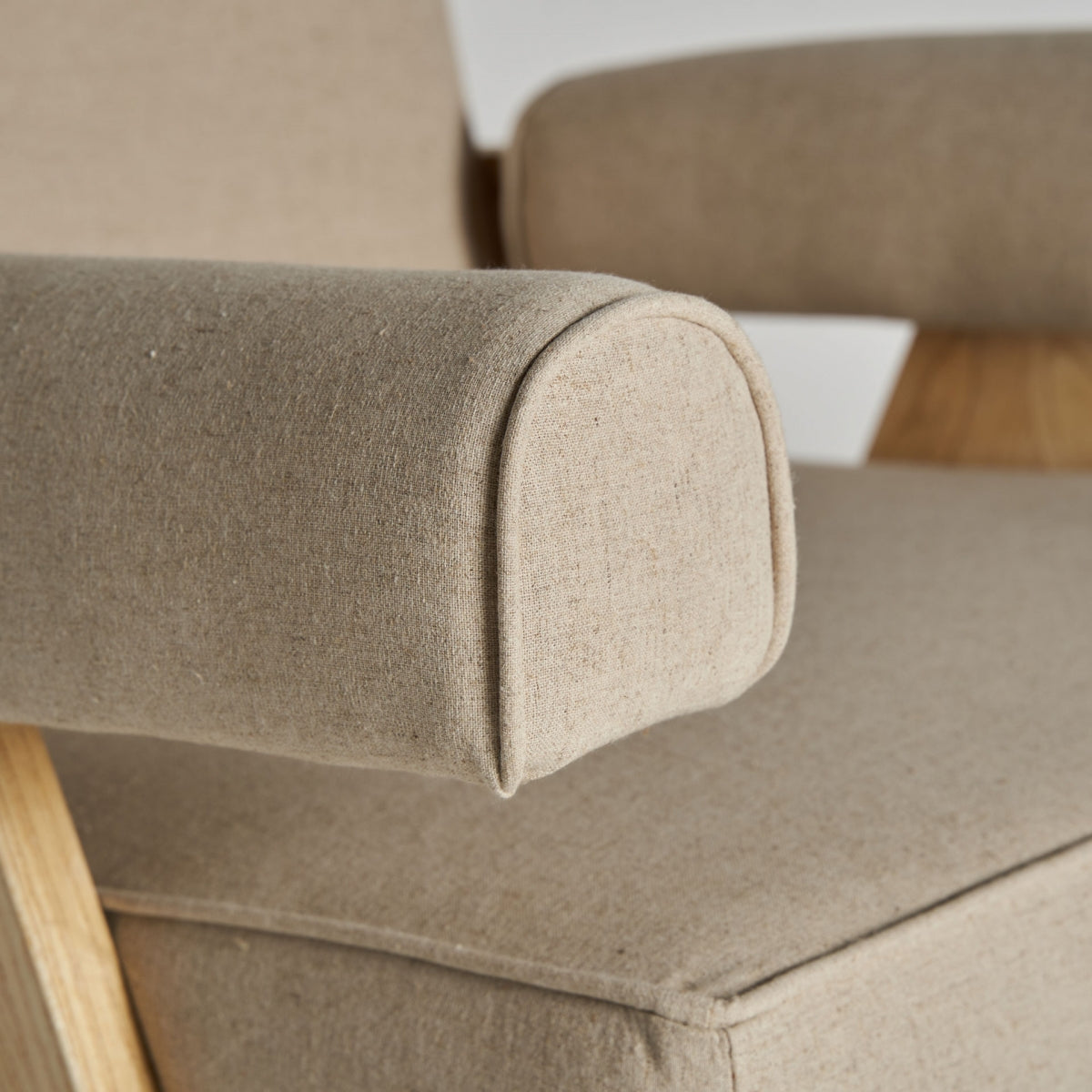 Detalle del apoyabrazos tapizado en lino beige del sillón, costuras visibles y acabado artesanal, boutique interiorismo vical