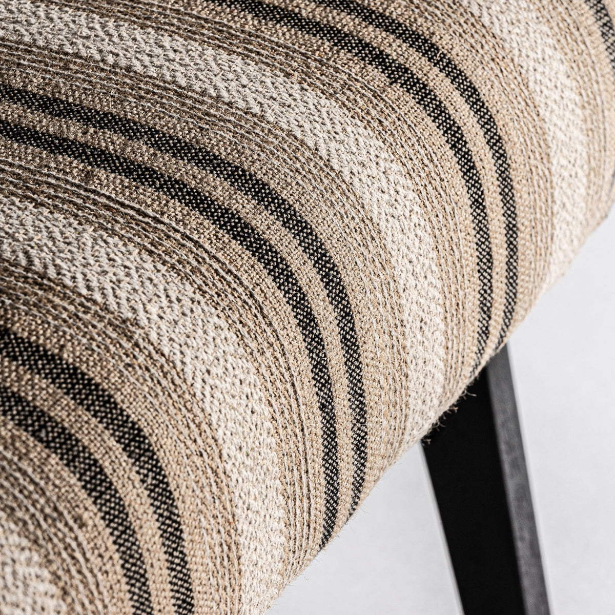 Detalle del asiento con tapizado de rayas en tonos neutros, textura rica y natural
