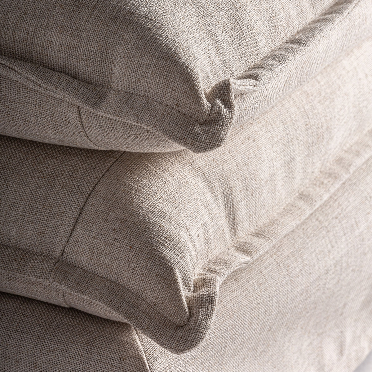 Detalle de los cojines en lino natural beige, textura suave y mullida