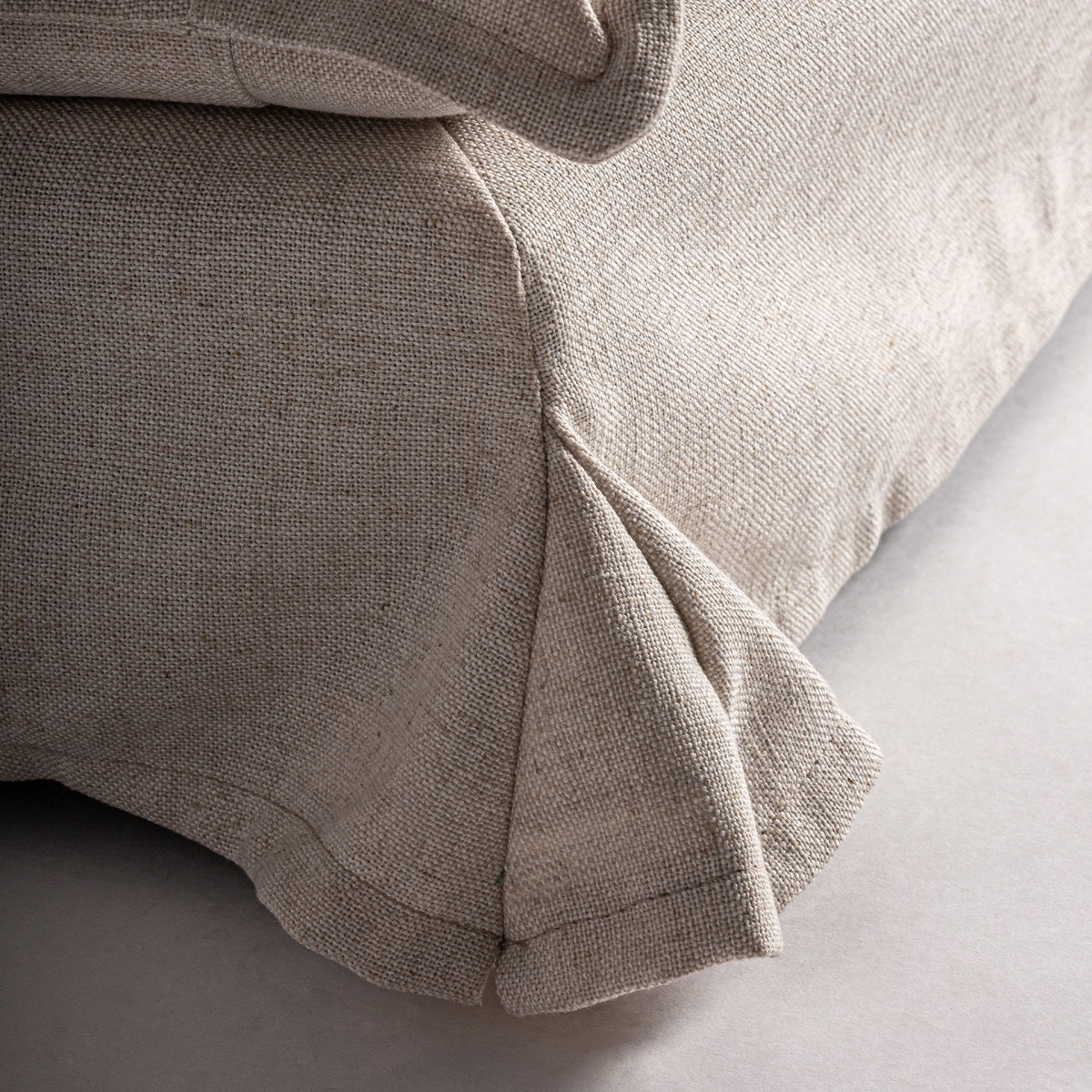 Detalle inferior con faldilla textil del sillón beige, acabado artesanal