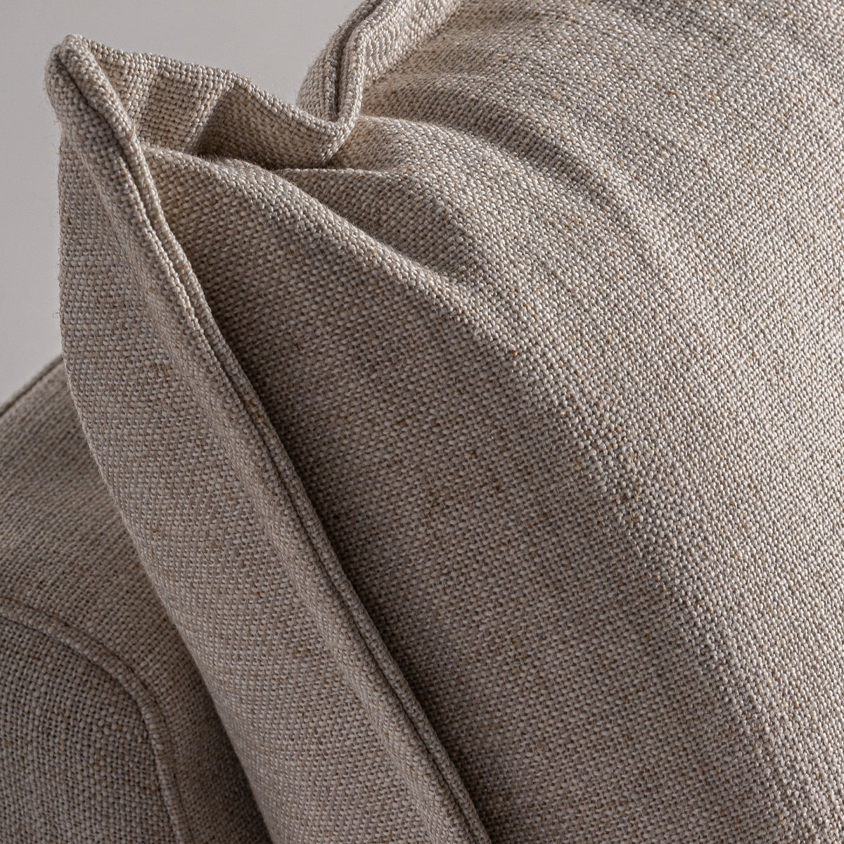Detalle del cojín respaldo en lino beige, costura marcada y textura natural