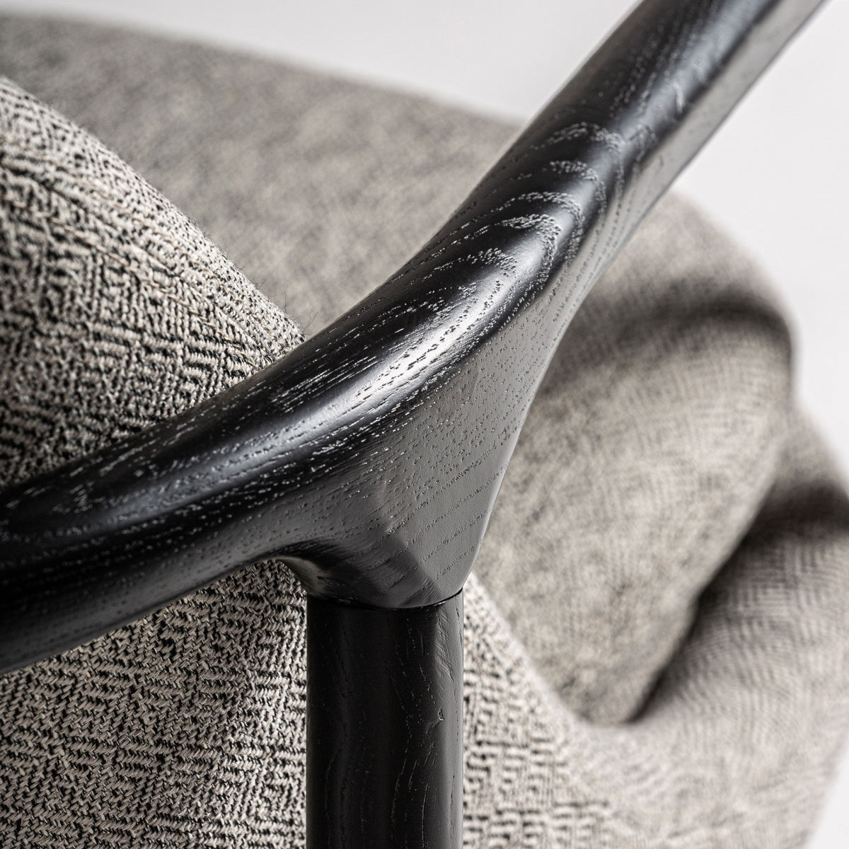 Detalle de brazo curvo en madera maciza negra, sensación de confort y diseño elegante
