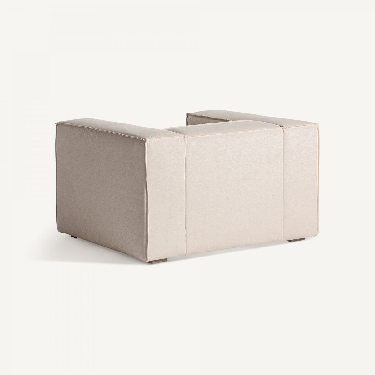 Vista trasera lateral del sillón Krakau, formas rectangulares y tapizado beige con costuras visibles