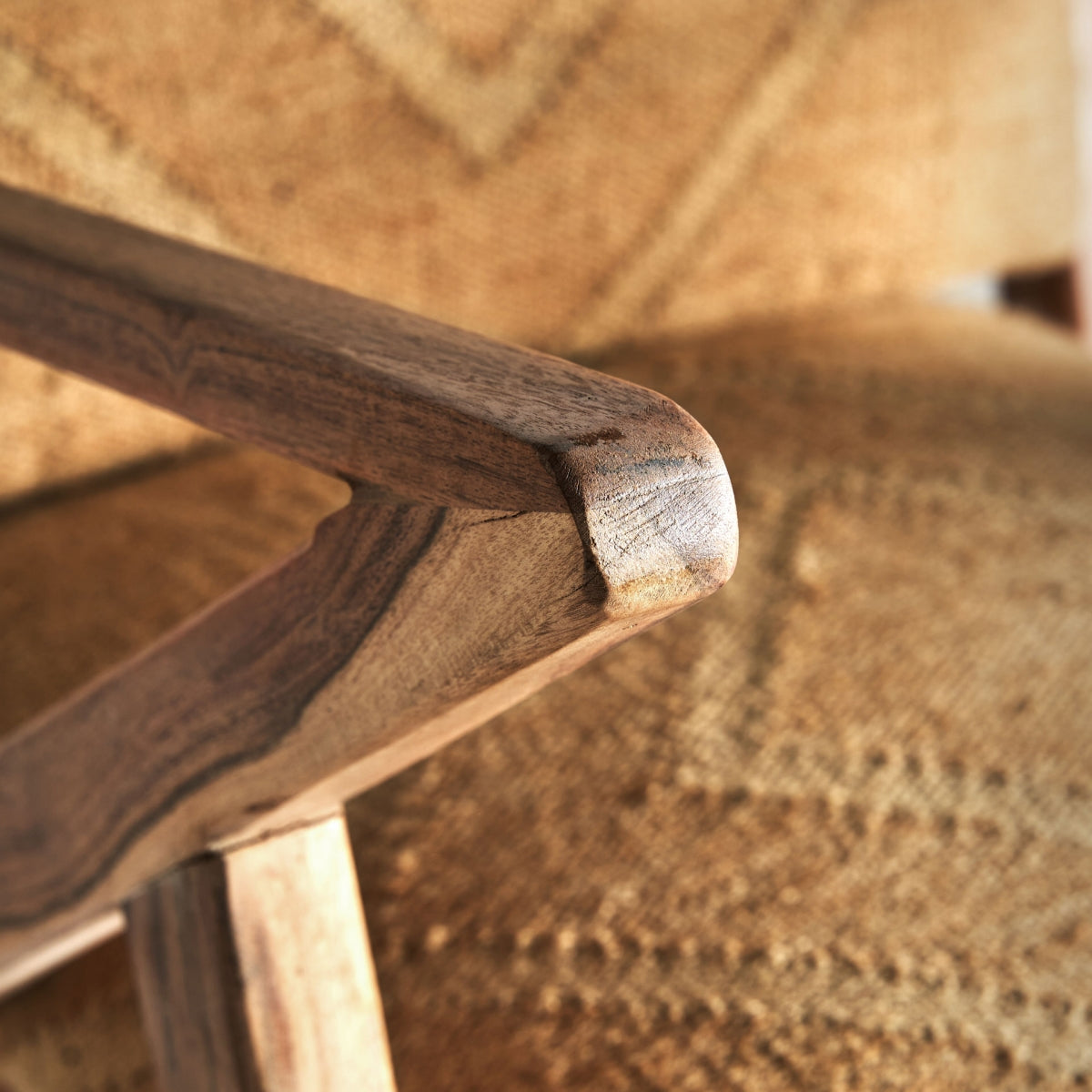 Detalle del brazo de madera natural de la butaca Elgin, acabado suave y curvo.