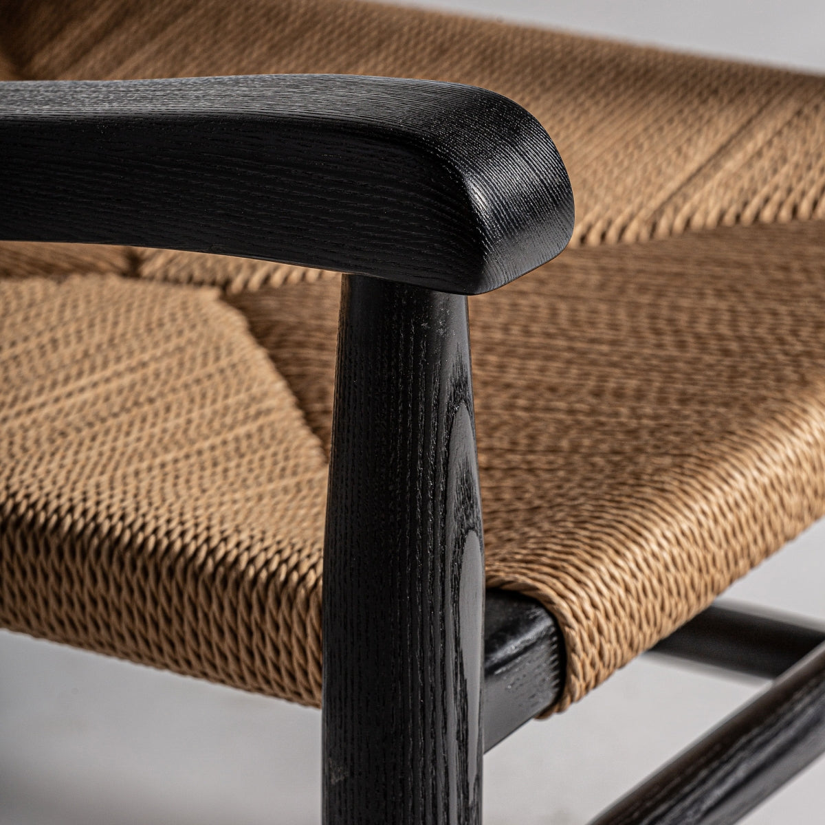 Detalle del apoyabrazos curvo en madera oscura, diseño orgánico