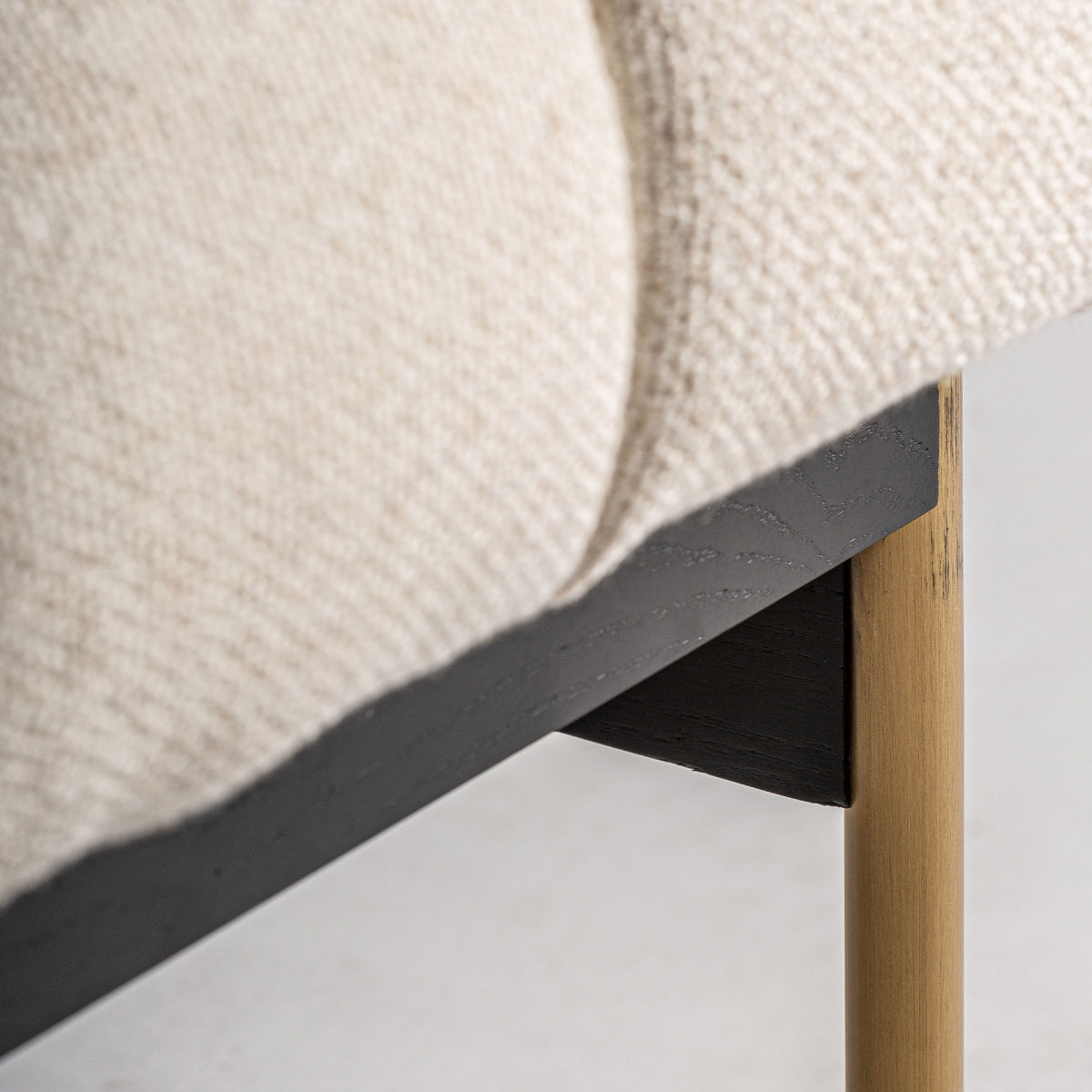 Detalle de la estructura en madera negra con pata de latón envejecido. Contraste de materiales cálido.