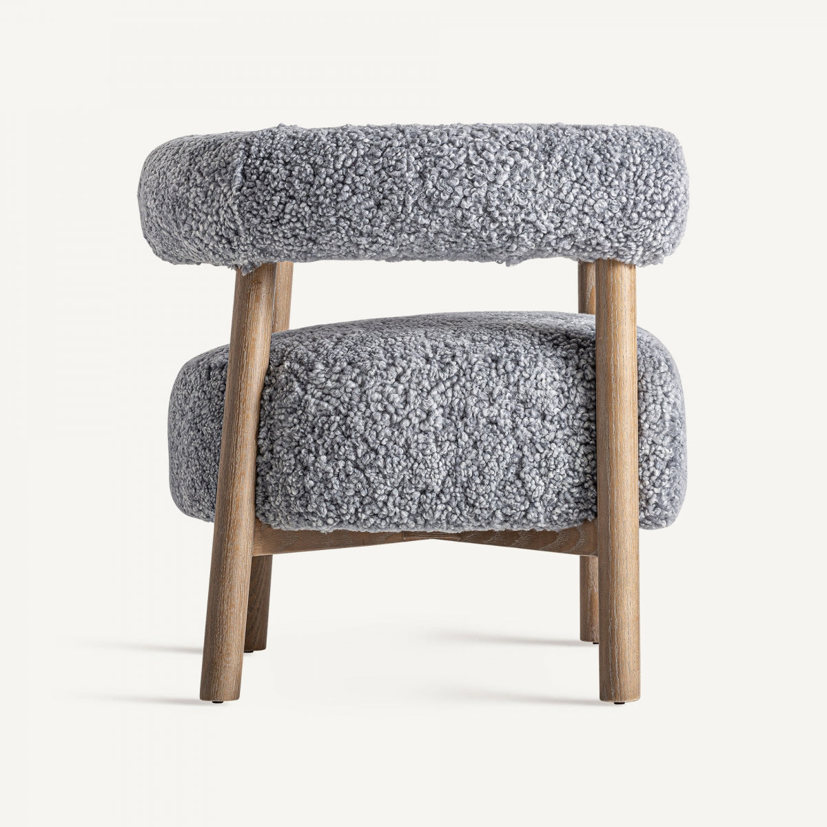 Vista lateral de butaca moderna boucle gris, respaldo curvo y patas de madera clara.