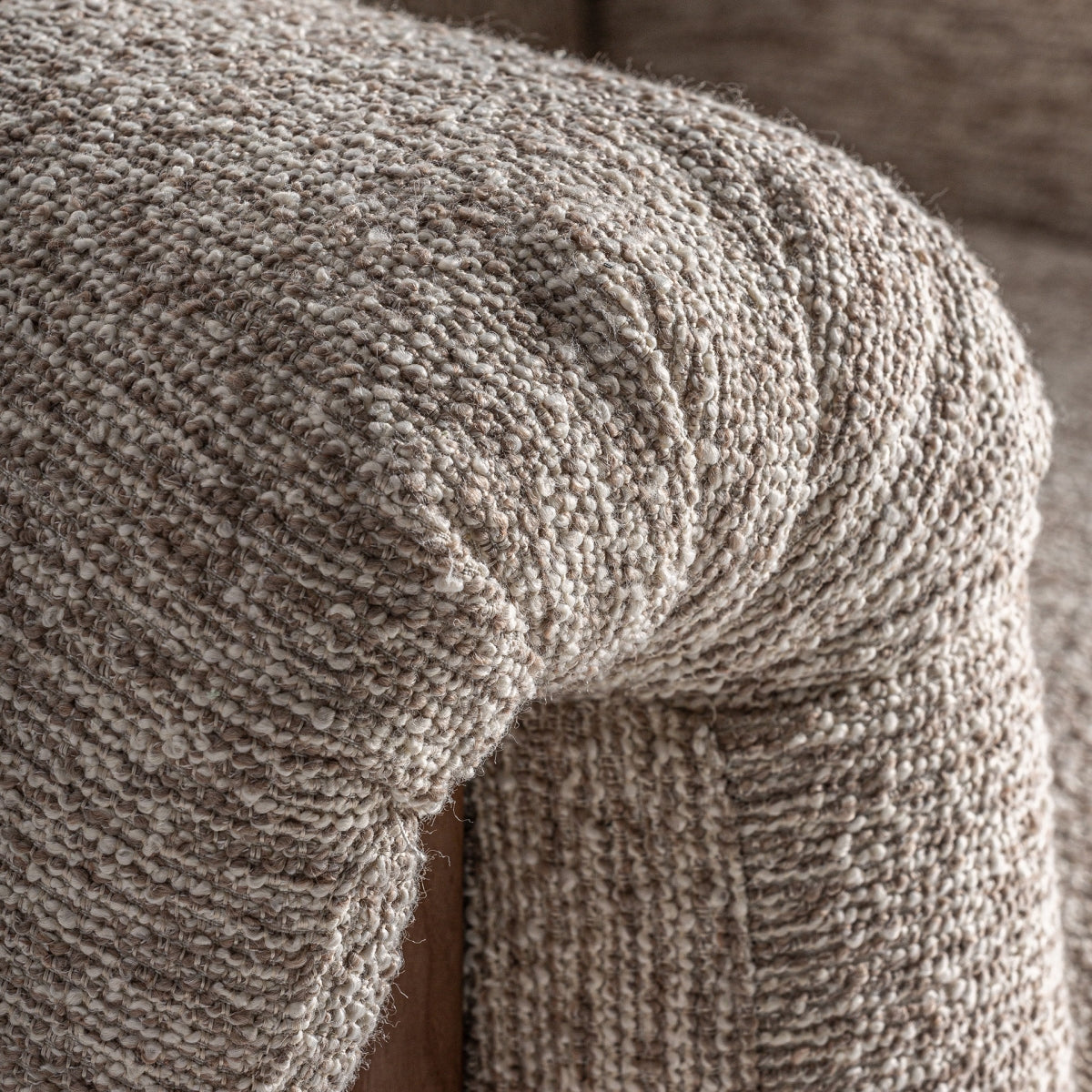 Primer plano del tapizado tipo bouclé en tono tierra del sillón UZNACH – textura natural y acogedora