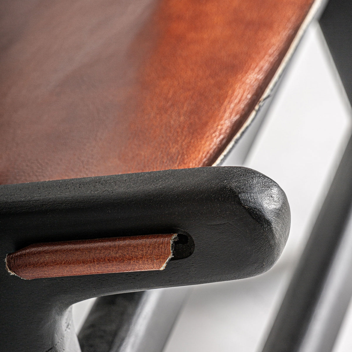 Primer plano del cuero natural marrón del asiento del sillón, con textura visible.