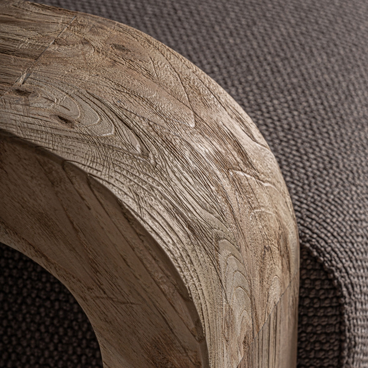 Detalle del brazo curvado en madera de teca con acabado natural y textura orgánica visible