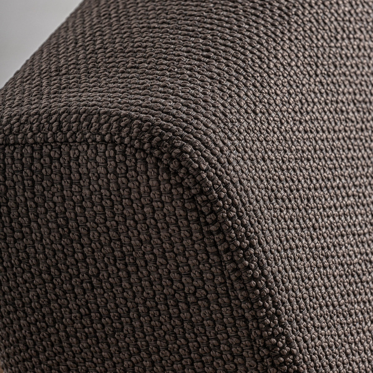 Detalle del canto redondeado del asiento tapizado, con textura marcada y acabado artesanal
