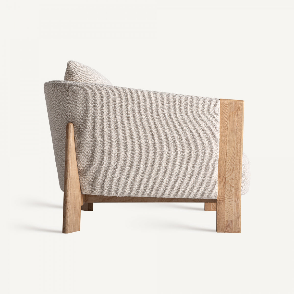 Vista lateral del sillón Nara con tapizado texturizado y estructura ergonómica de madera