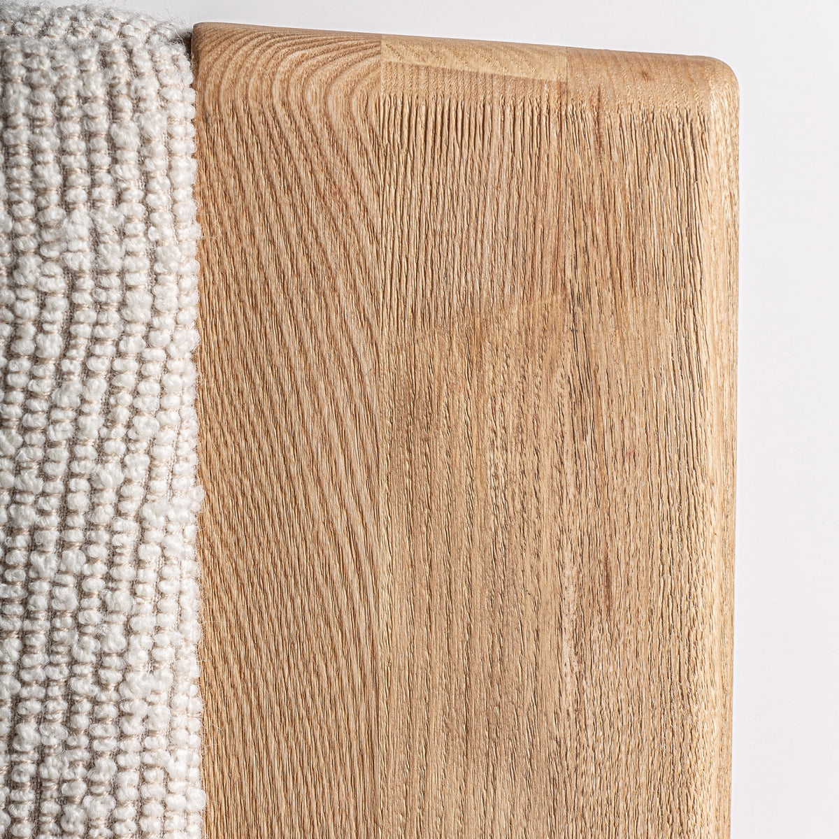 Vista superior del acabado de madera natural del respaldo del sillón Nara con unión de tapizado