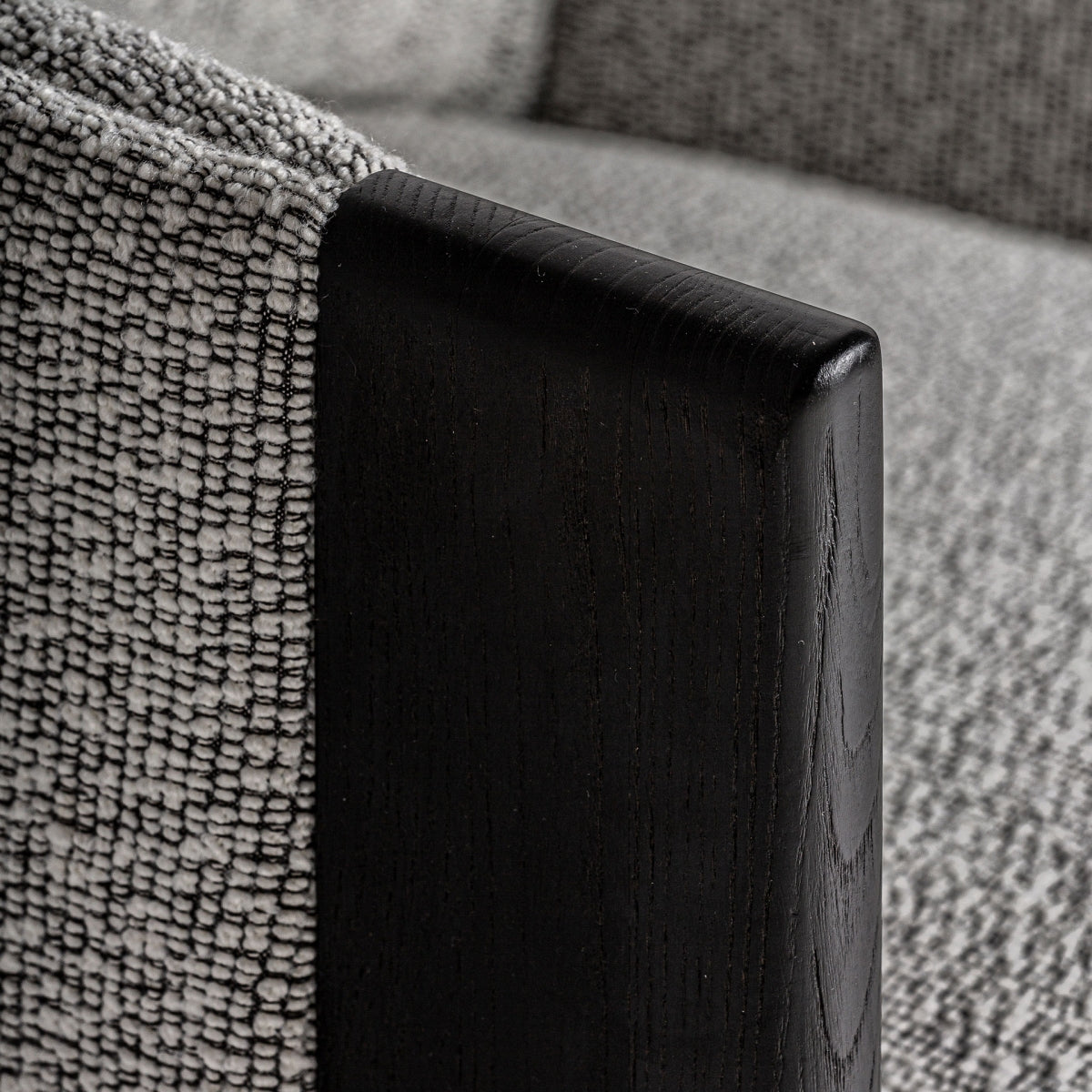 Primer plano del brazo en madera negra del sillón Nara con vetas visibles y acabado mate