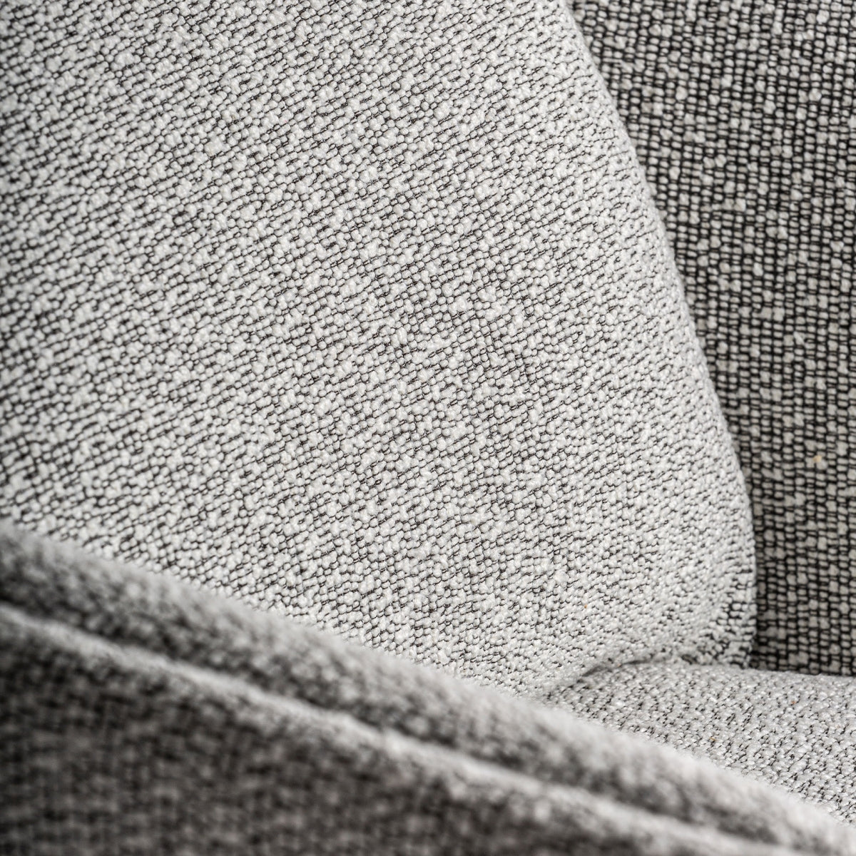 Detalle del respaldo acolchado del sillón Nara, con textura bouclé gris y formas suaves