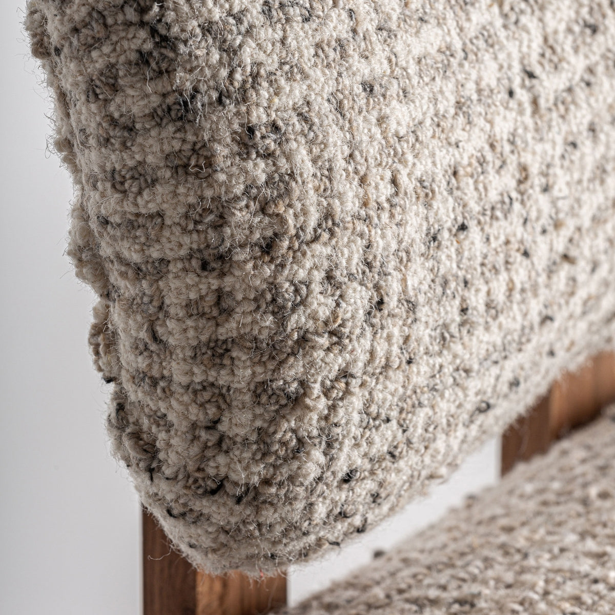Primer plano del respaldo curvado tapizado en tejido bouclé, detalle de textura y forma, boutique interiorismo Vical
