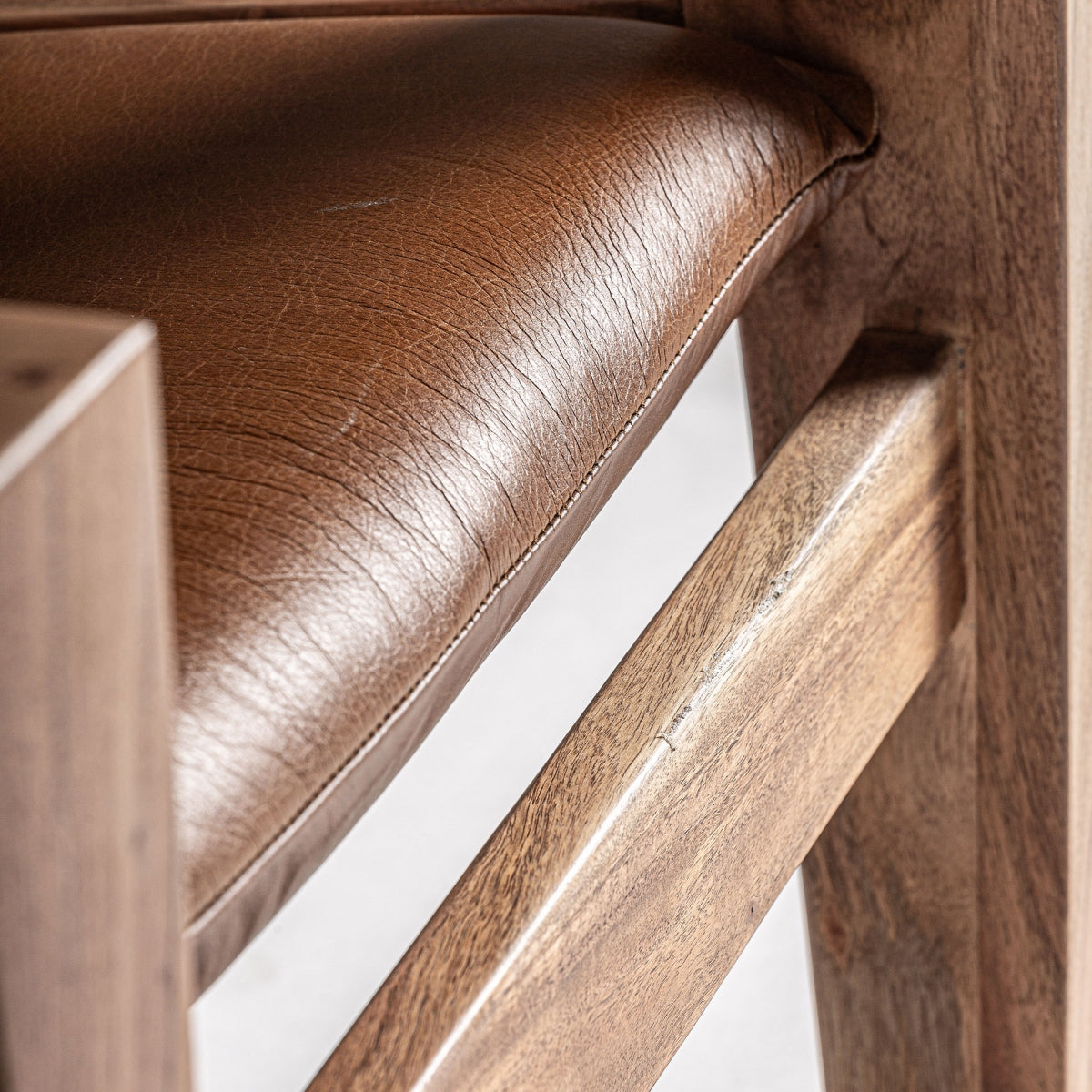Detalle del asiento del sillón MELLE con tapizado en cuero marrón de textura natural