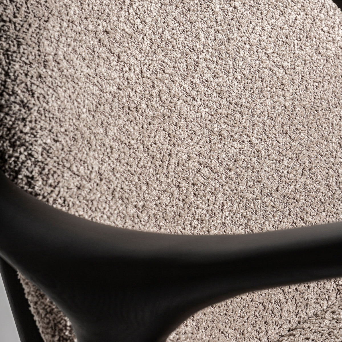 Primer plano del respaldo en bouclé del sillón, textura mullida y acogedora