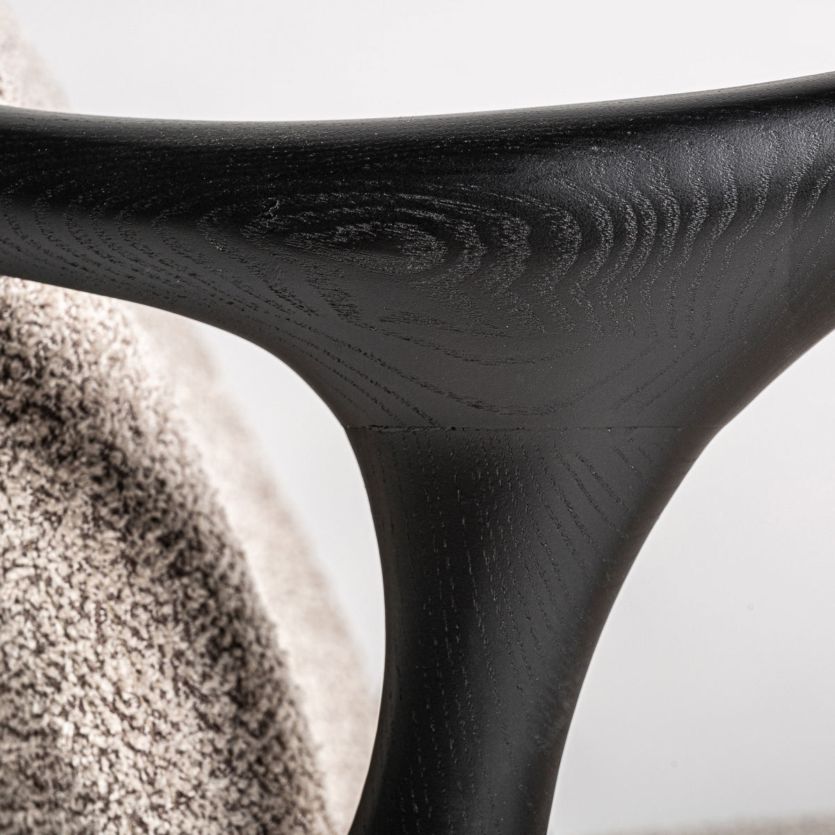 Detalle en madera curva negra del brazo del sillón con vetas visibles