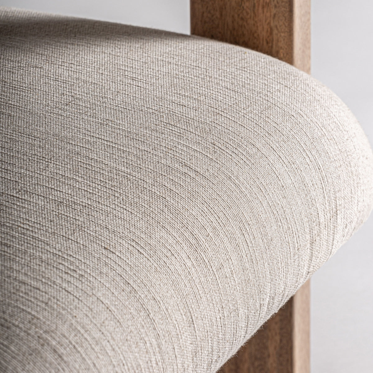 Detalle del asiento curvo tapizado en tejido beige sobre estructura de madera – confort visual y elegancia boutique interiorismo vical