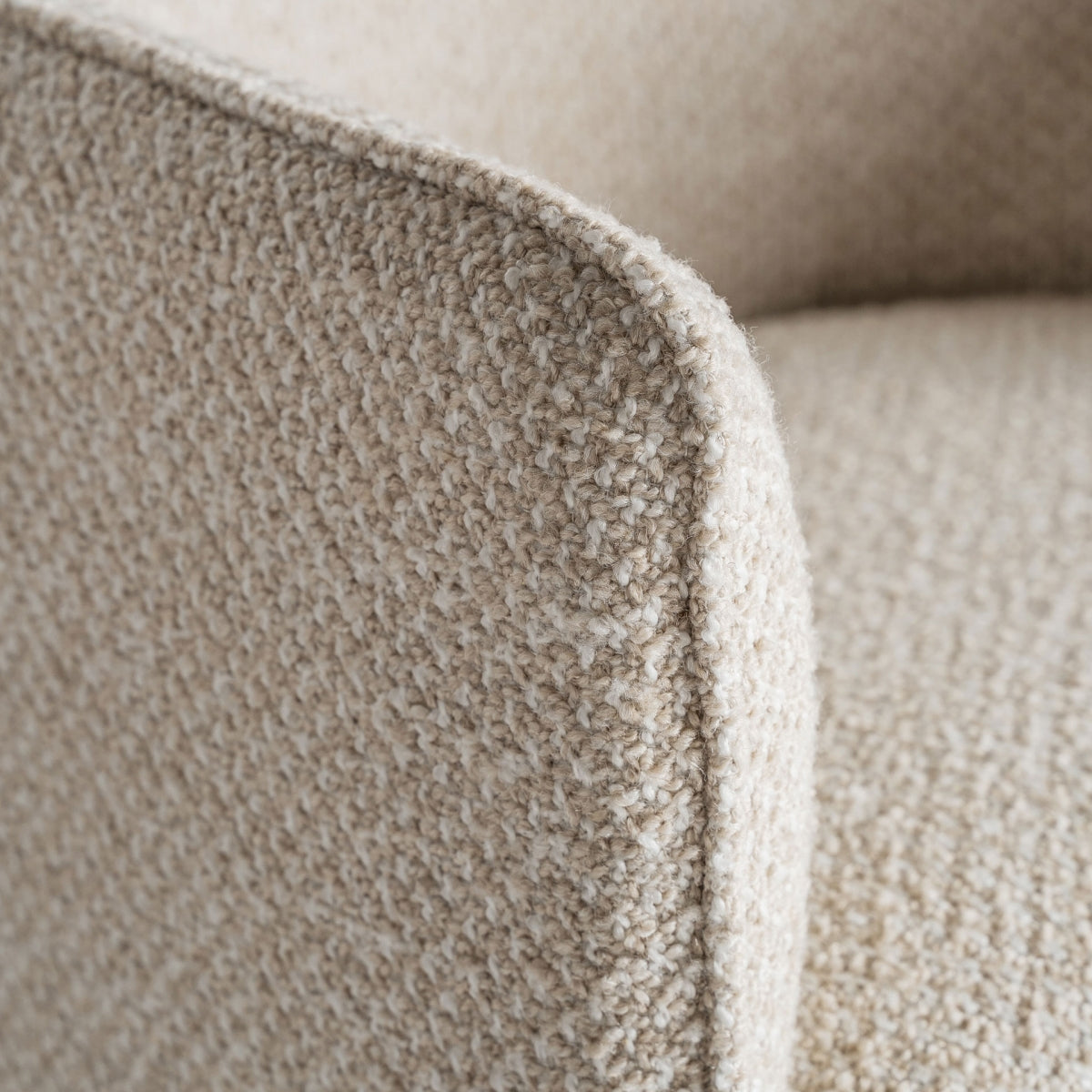 Detalle del asiento redondeado del sillón Mayun en beige con sutil ribete dorado