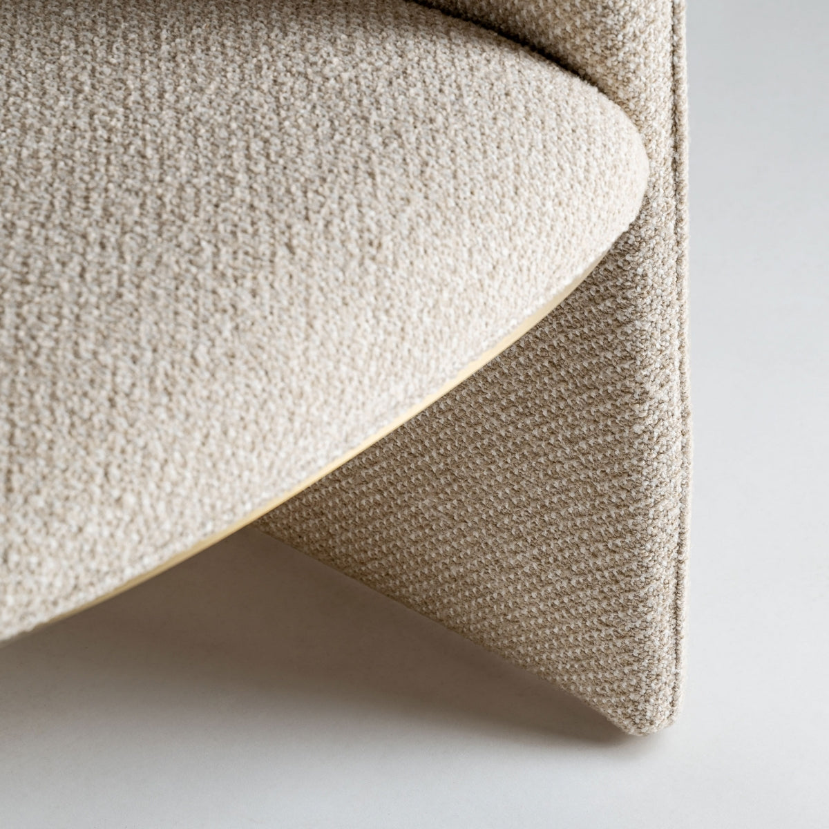 Detalle del brazo curvo tapizado en poliéster beige con textura suave