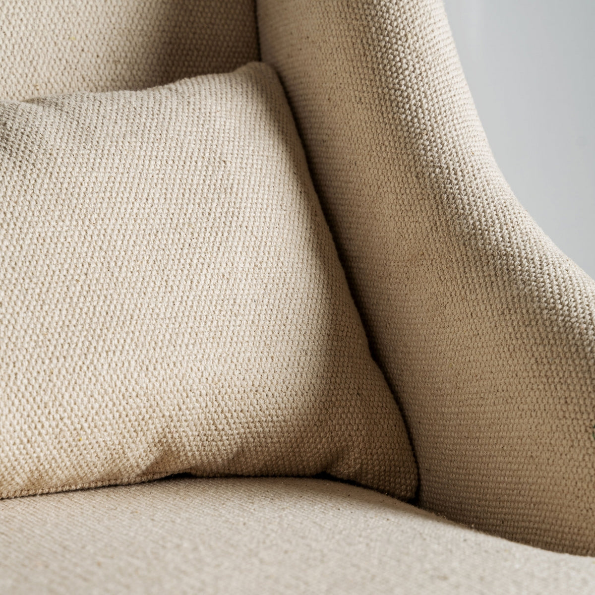 Detalle de cojín y tapizado texturizado en sillón beige, tejido natural de aspecto cálido