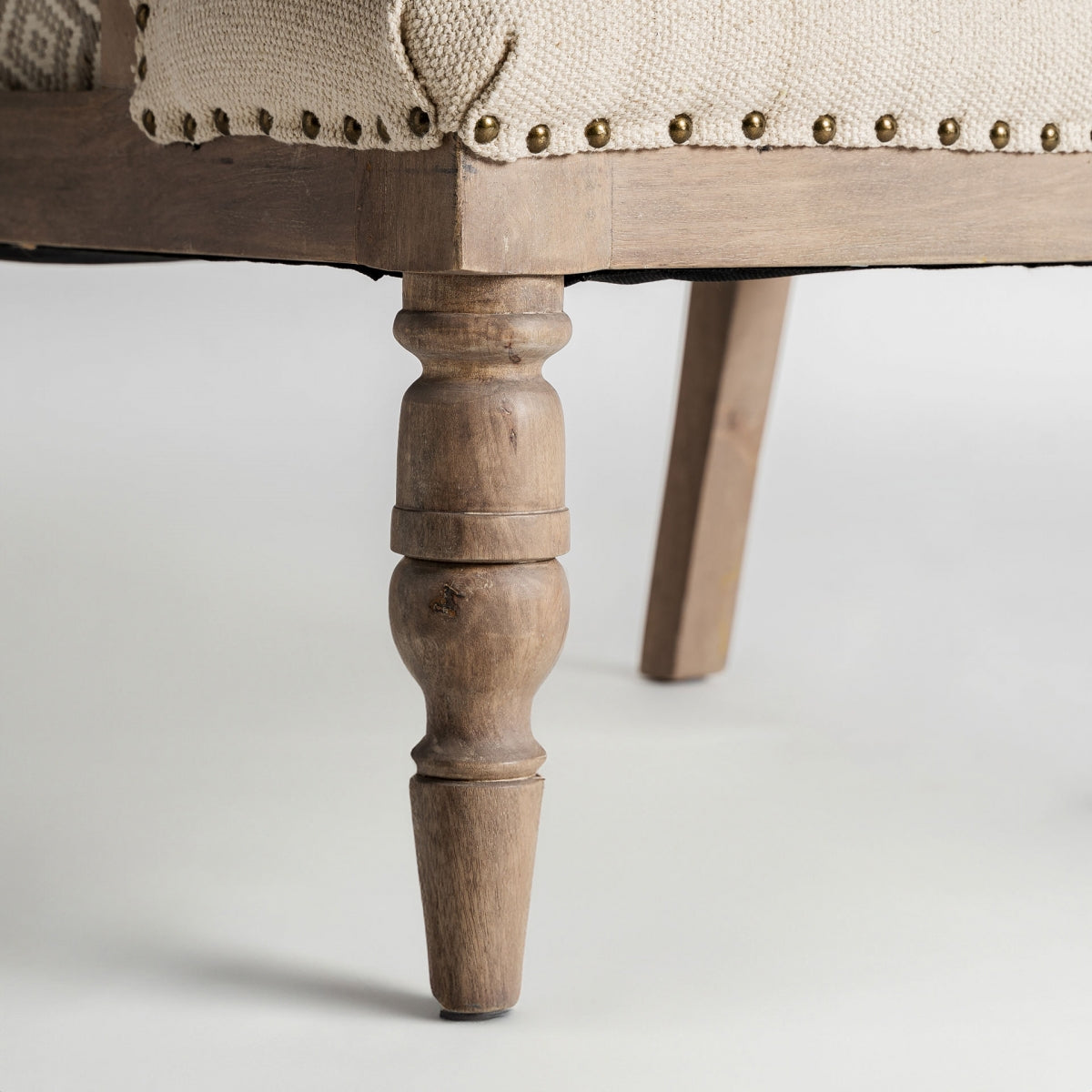 Detalle de pata torneada en madera natural, estructura robusta y elegante del sillón