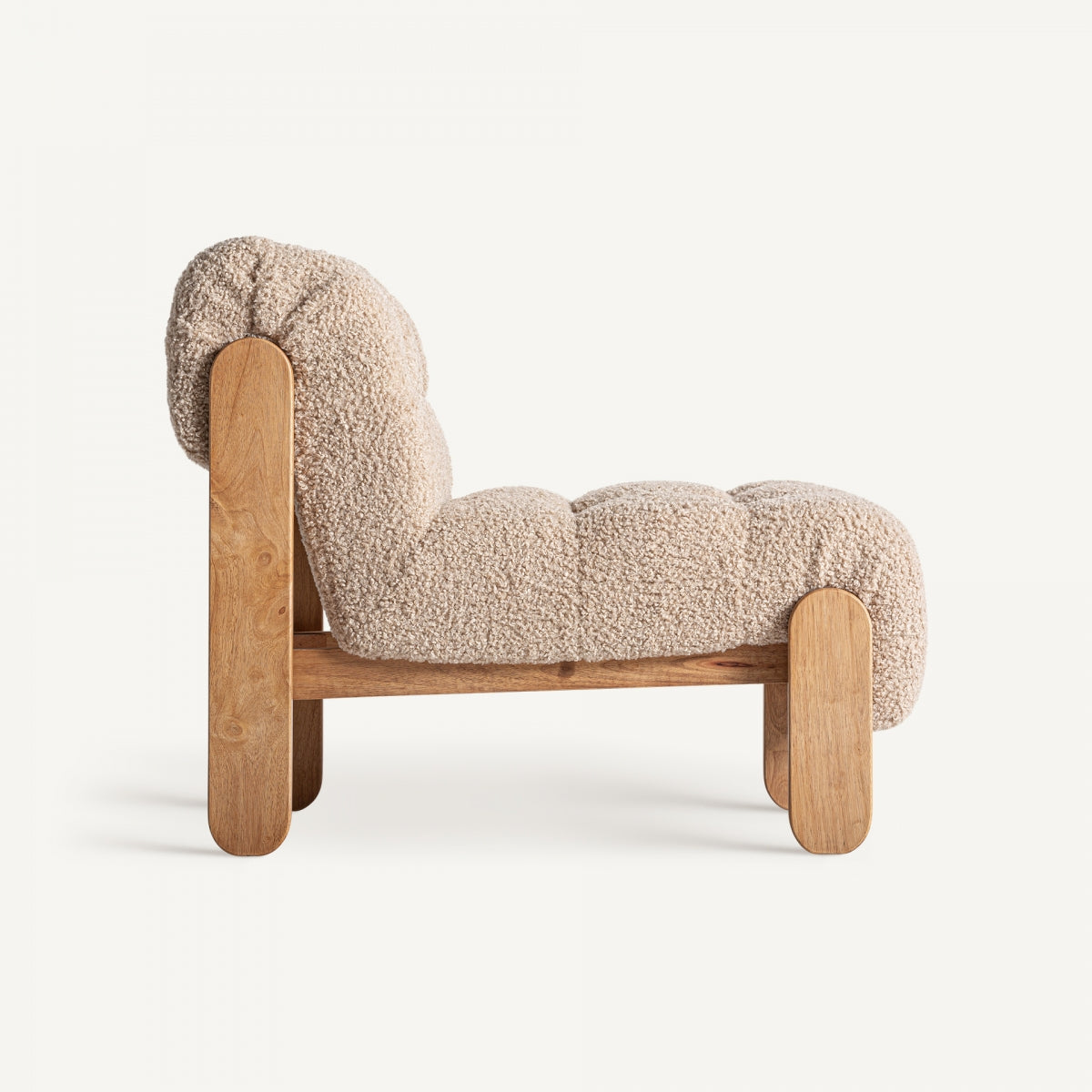 Perfil lateral de la butaca Neyprat en madera clara y bouclé, asiento bajo y respaldo envolvente, diseño cálido