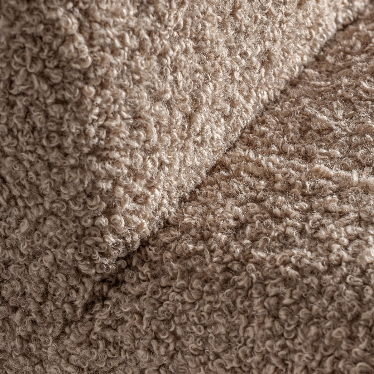 Detalle cercano del tejido bouclé rizado en tono beige de la butaca Neyprat, textura suave y acogedora
