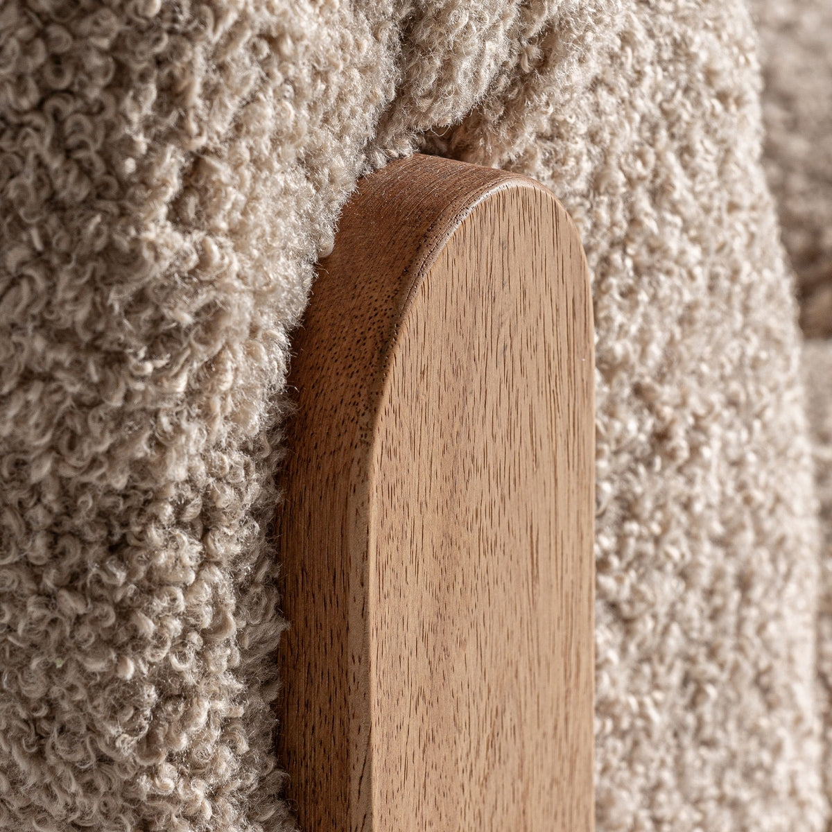 Detalle lateral de la estructura redondeada en madera y tejido bouclé de la butaca Neyprat, estilo orgánico cálido