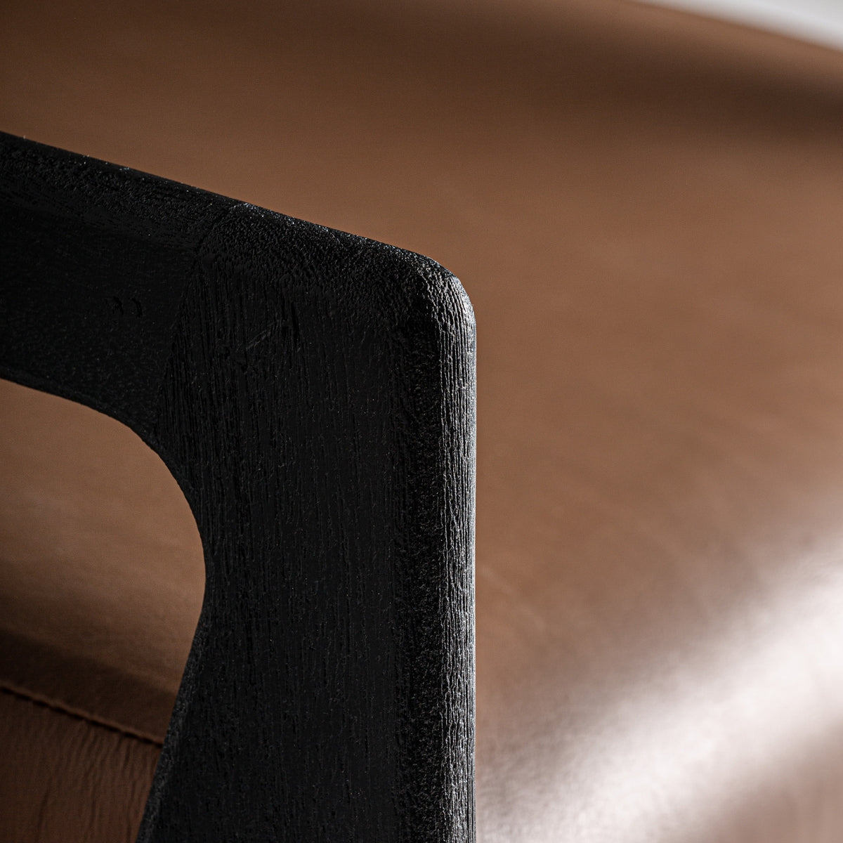 Detalle del brazo en madera negra con textura marcada y acabado artesanal