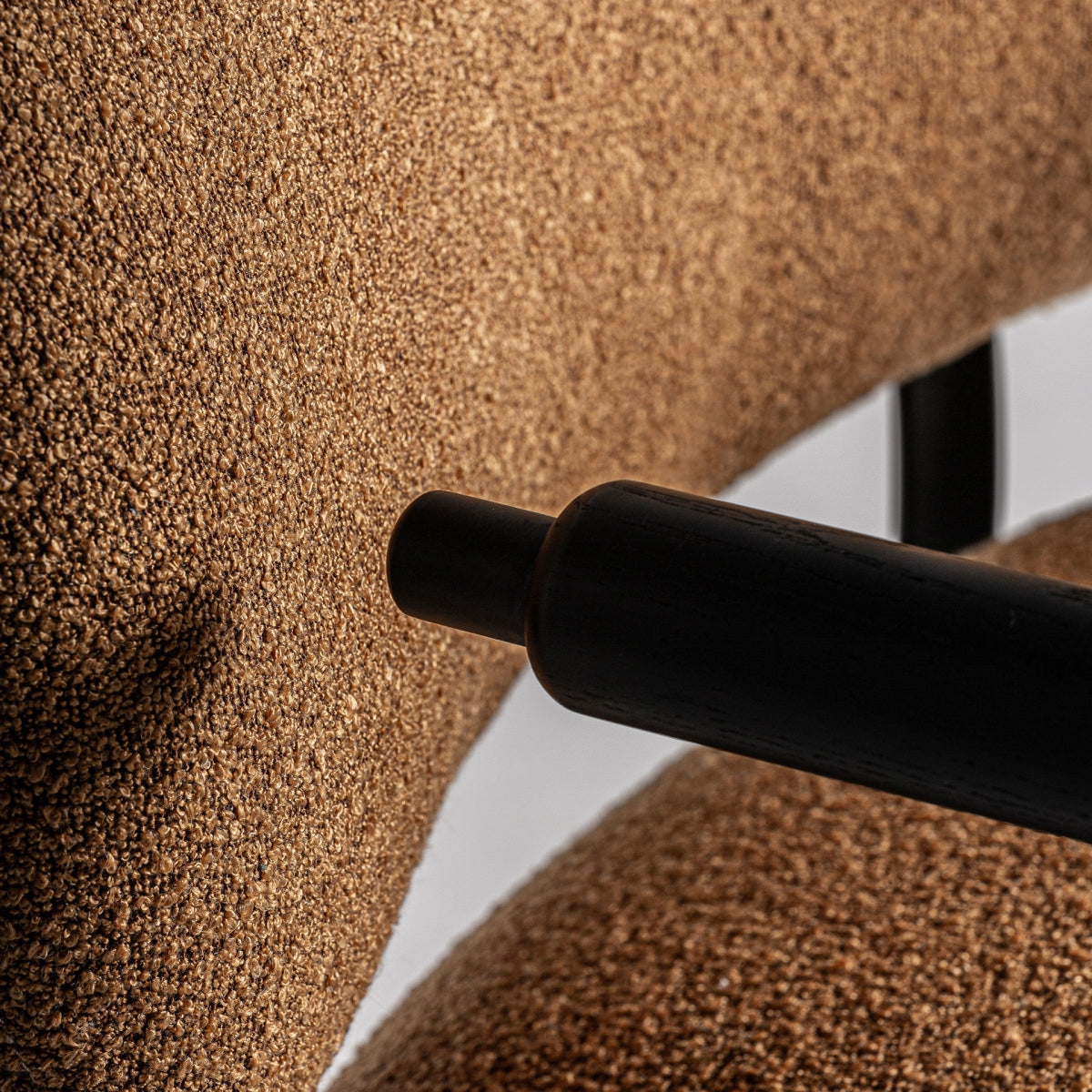 Detalle del anclaje del apoyabrazos al respaldo tapizado en boucle color camel