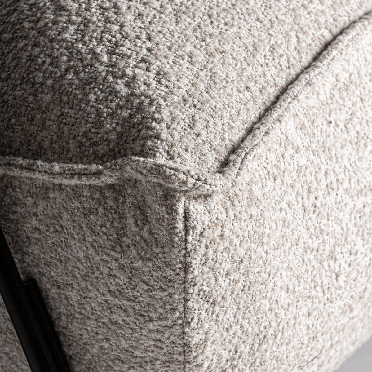 Detalle del cojín tapizado en boucle con textura suave y costuras visibles