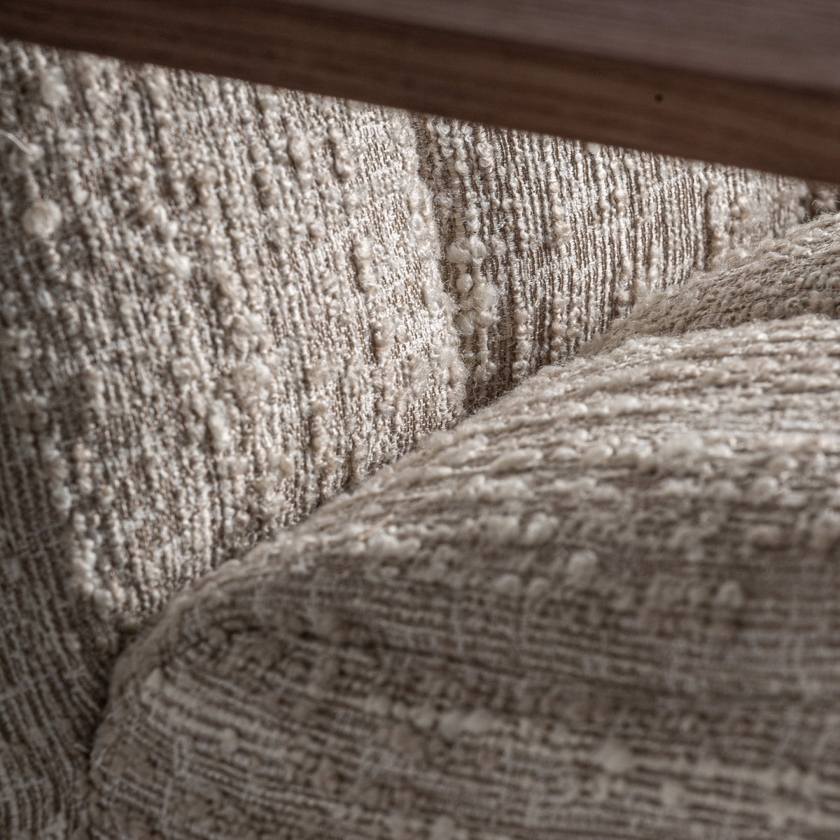 Textura del tapizado bouclé en tono beige. Superficie mullida y acogedora.