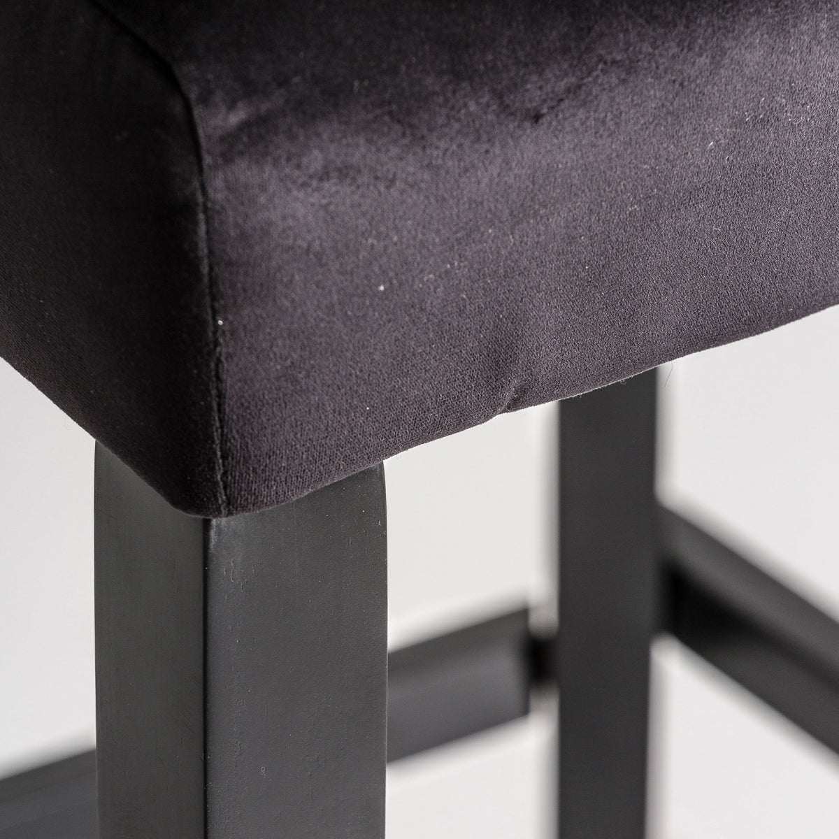 Detalle de la estructura de madera negra del taburete, unión sólida y estética contemporánea.