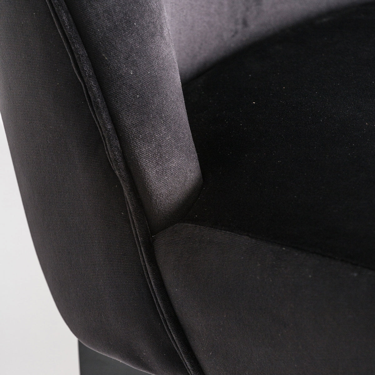 Detalle del respaldo curvado y tapizado suave del taburete en terciopelo negro.