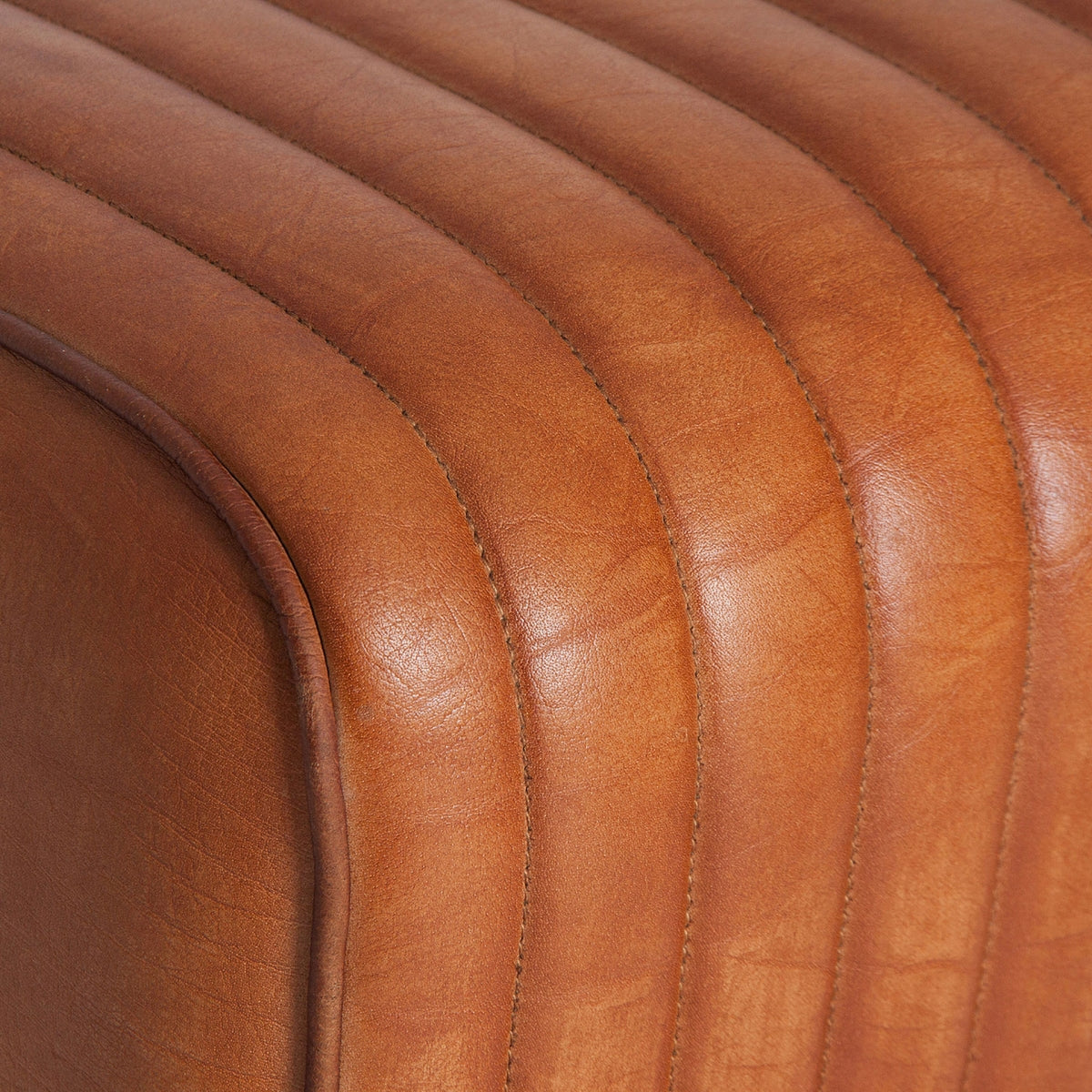 Detalle del asiento acanalado en cuero marrón, acabado artesanal y textura envejecida.