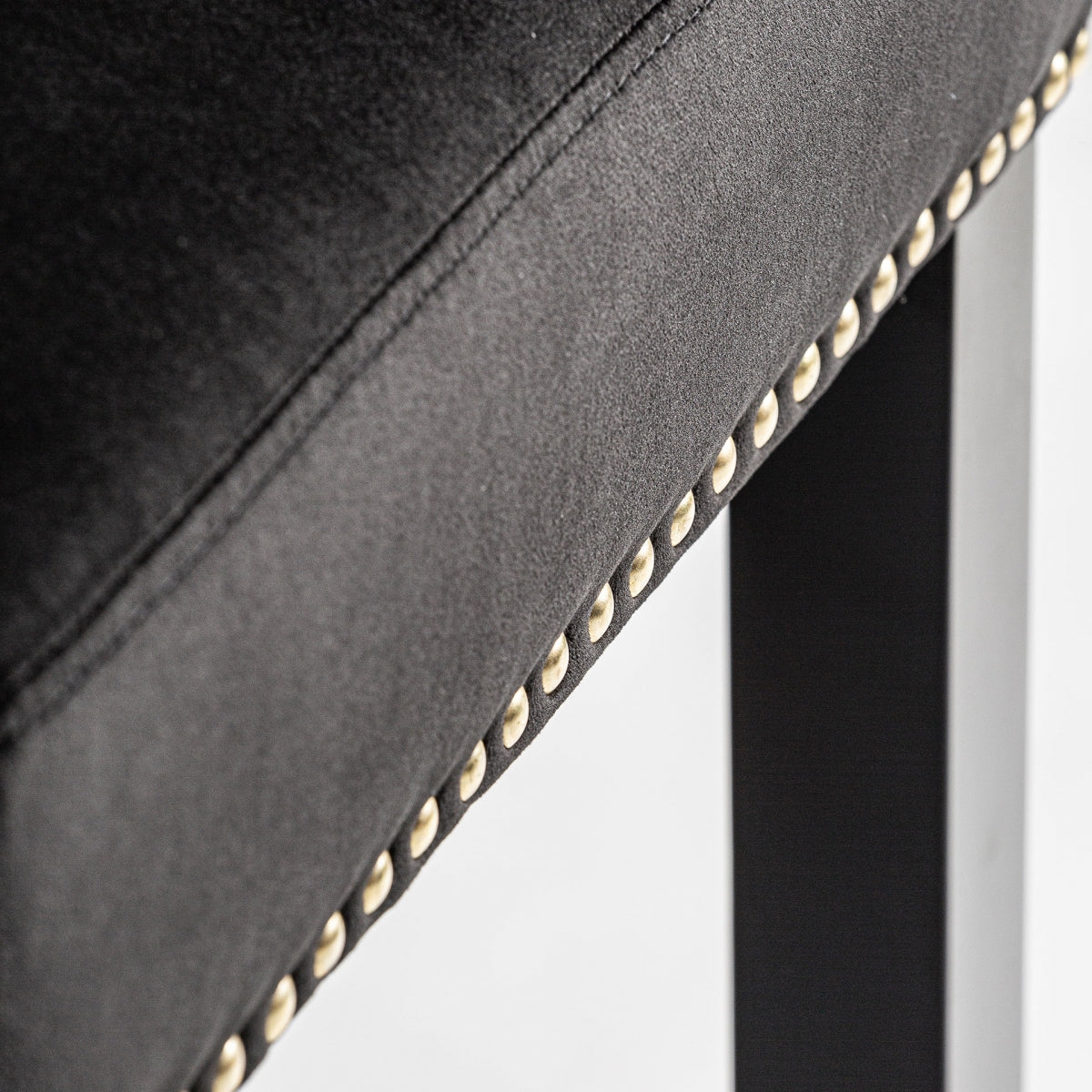 Detalle lateral del asiento con tapizado de terciopelo negro y tachuelas doradas alineadas