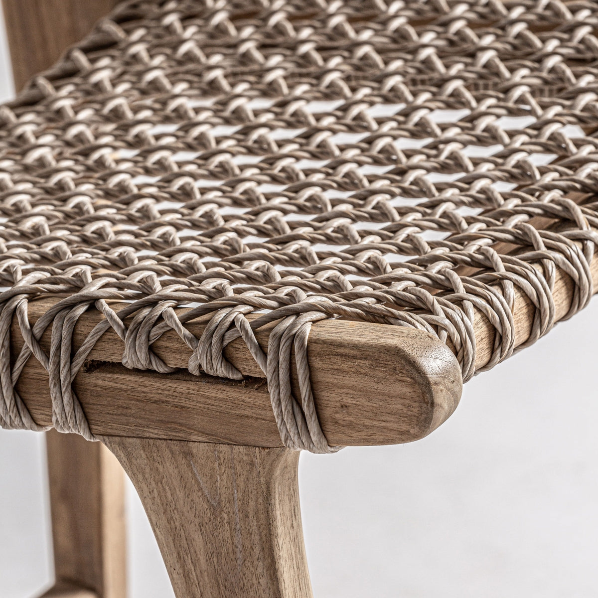 Detalle de la esquina del asiento trenzado a mano sobre estructura de madera, estilo artesanal y bohemio.