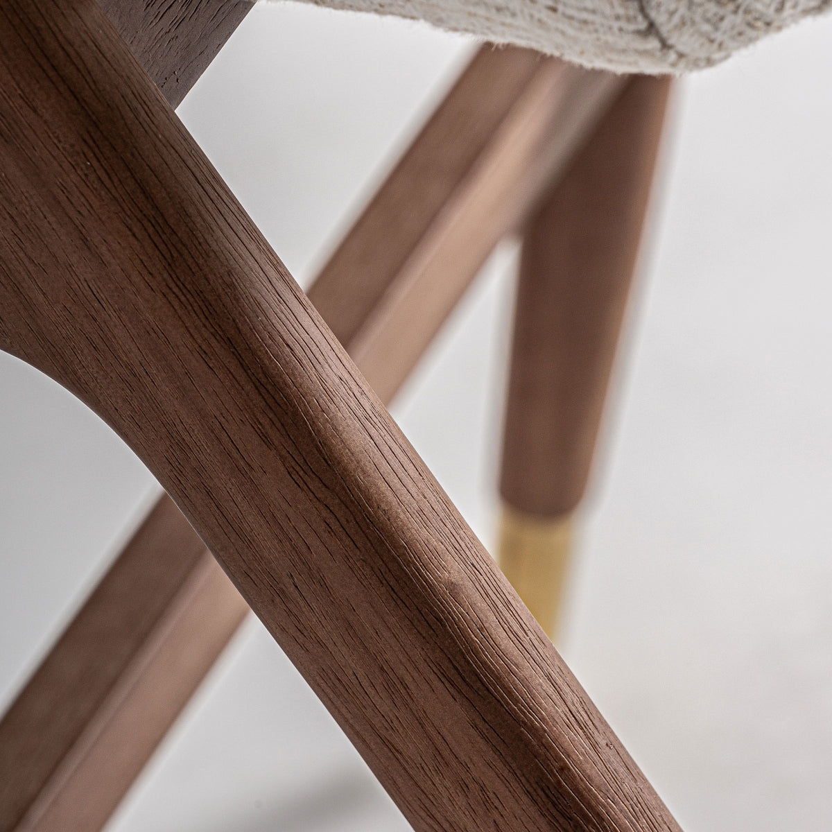 Detalle de la estructura de madera de nogal y patas con terminación en latón, diseño sofisticado.