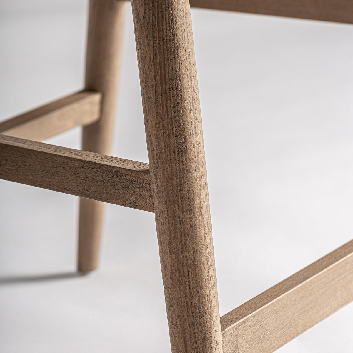 Detalle del asiento de bouclé sobre estructura de madera natural con acabado liso.